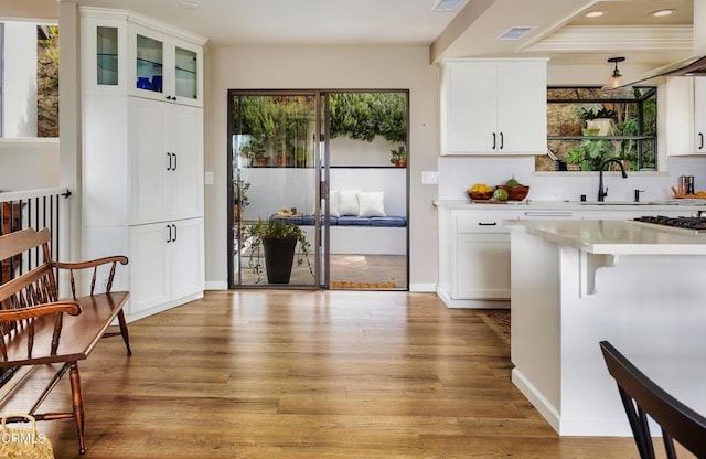 kitchen with a sink, visible vents, white cabinets, light countertops, and light wood-type flooring