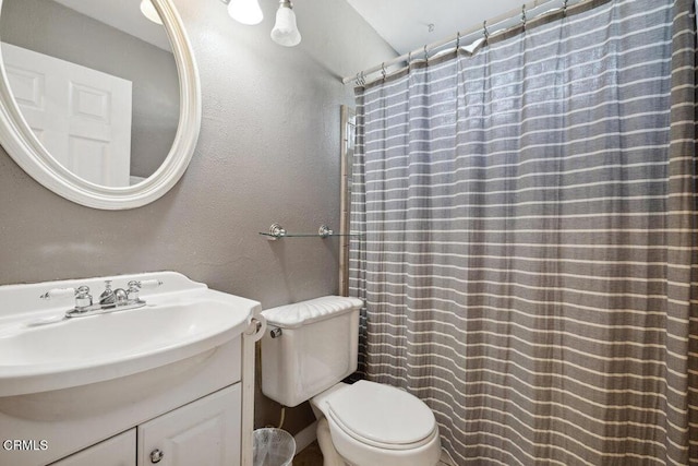 bathroom with toilet, a textured wall, a shower with shower curtain, and vanity