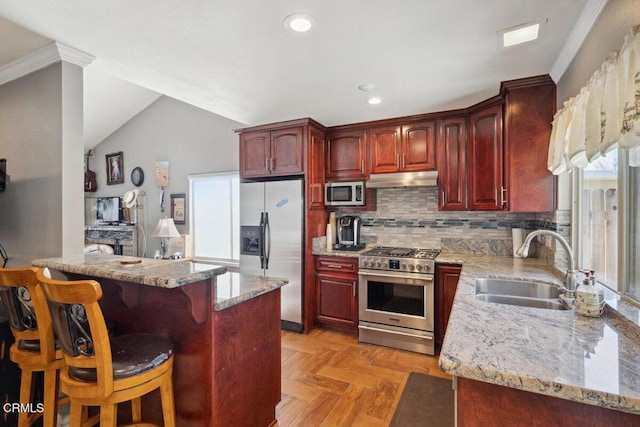 kitchen featuring reddish brown cabinets, stainless steel appliances, a sink, and under cabinet range hood