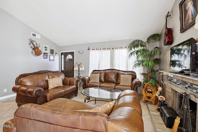 living area featuring visible vents, a tiled fireplace, light tile patterned flooring, vaulted ceiling, and baseboards