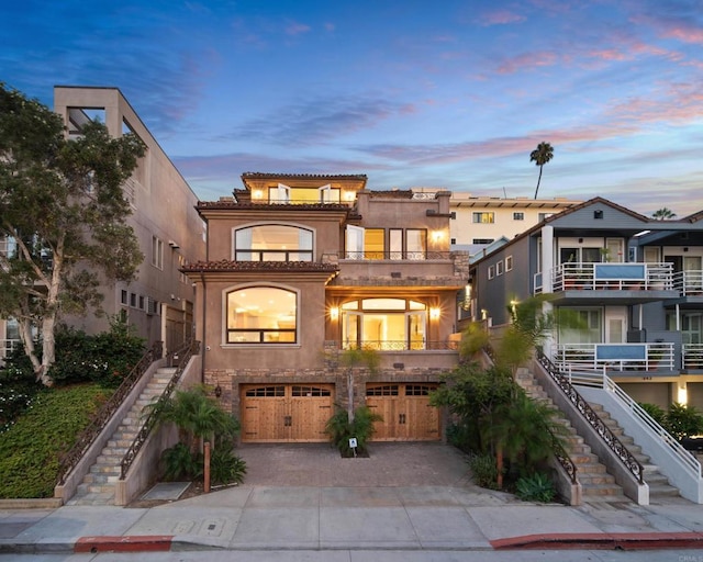 view of front of home with decorative driveway, stucco siding, stairway, an attached garage, and a tiled roof