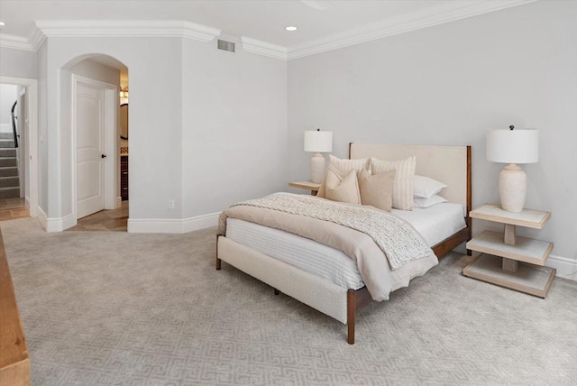 bedroom with carpet floors, arched walkways, visible vents, ornamental molding, and baseboards