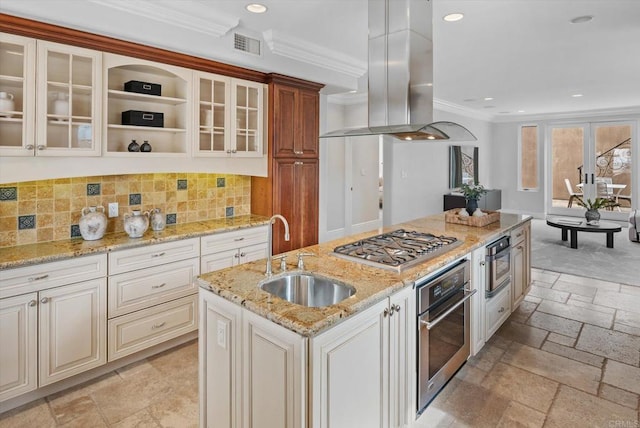 kitchen with a sink, appliances with stainless steel finishes, island exhaust hood, stone tile flooring, and crown molding