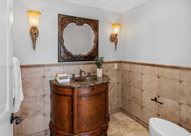 bathroom featuring toilet, a wainscoted wall, vanity, tile walls, and ornamental molding