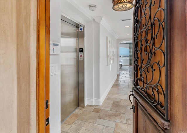 corridor featuring baseboards, elevator, crown molding, stone tile flooring, and recessed lighting