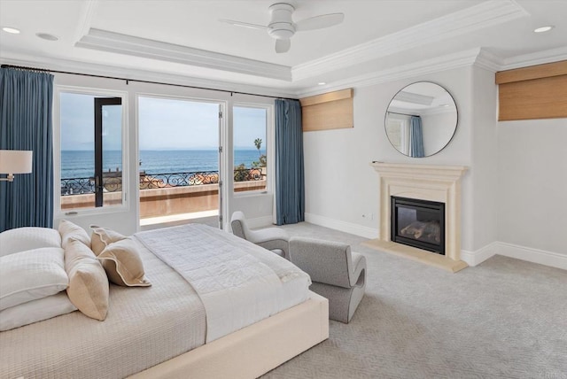 bedroom featuring carpet, a raised ceiling, and a glass covered fireplace