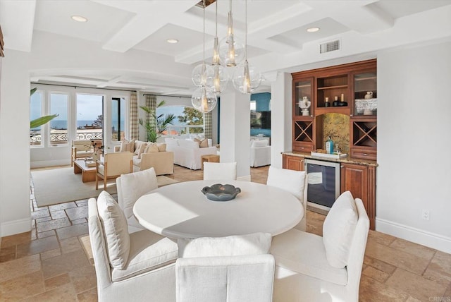 dining room featuring stone tile flooring, beverage cooler, visible vents, and baseboards