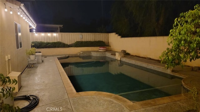 pool at night with a fenced in pool and a fenced backyard