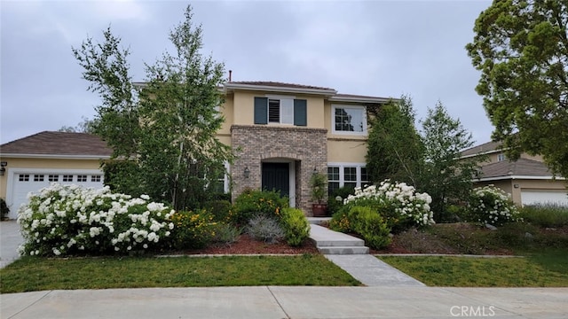 view of front of house featuring a garage, brick siding, and stucco siding