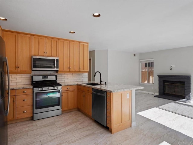 kitchen featuring a peninsula, a sink, open floor plan, appliances with stainless steel finishes, and tasteful backsplash