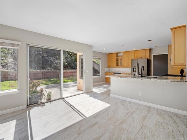 kitchen with recessed lighting, decorative backsplash, stainless steel fridge, a peninsula, and baseboards