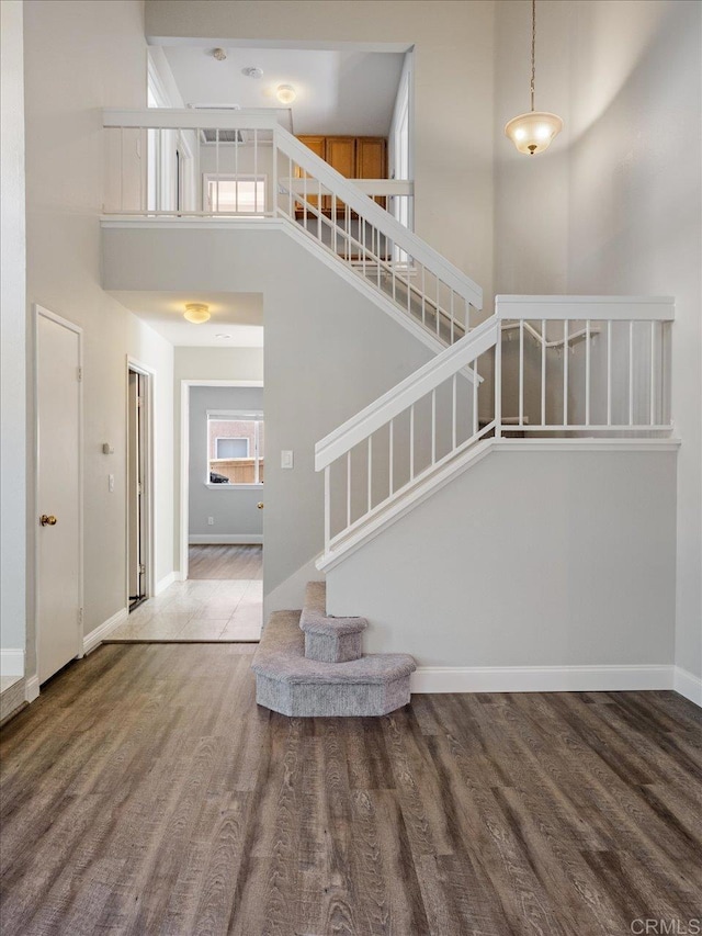 interior space featuring a towering ceiling, baseboards, and wood finished floors