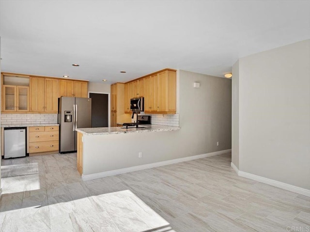 kitchen with light stone counters, stainless steel appliances, decorative backsplash, a peninsula, and baseboards