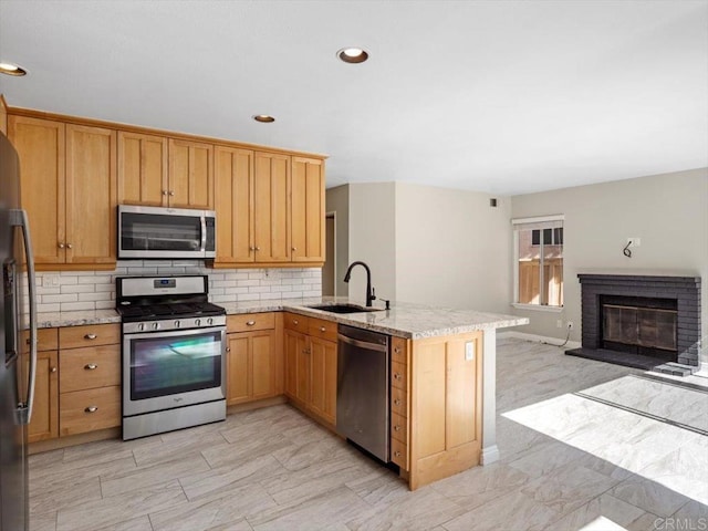 kitchen featuring tasteful backsplash, appliances with stainless steel finishes, open floor plan, a sink, and a peninsula