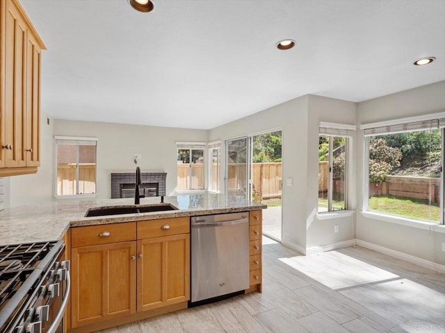 kitchen with a peninsula, appliances with stainless steel finishes, a sink, and a healthy amount of sunlight