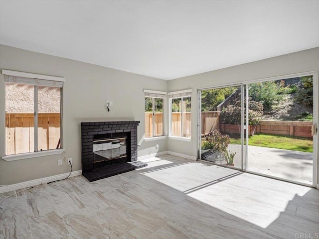 unfurnished living room with a brick fireplace and baseboards