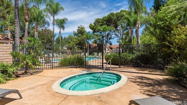 pool featuring fence and a hot tub