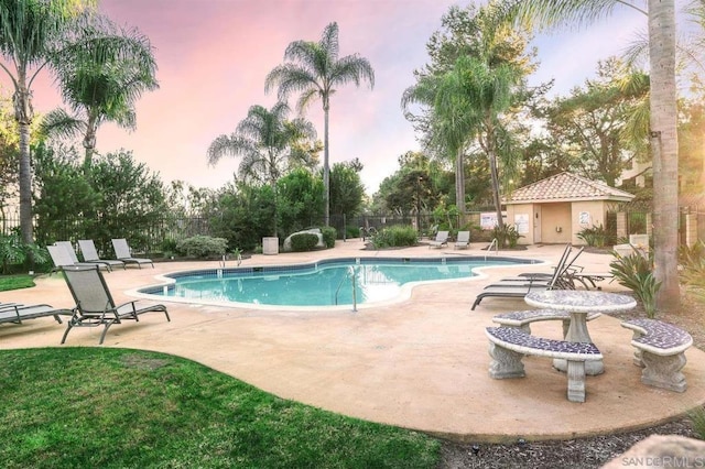 community pool with a patio area and fence