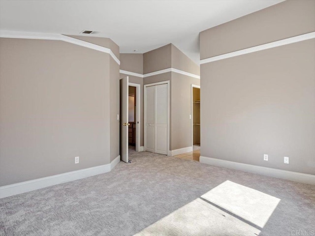 unfurnished bedroom with lofted ceiling, baseboards, and light colored carpet