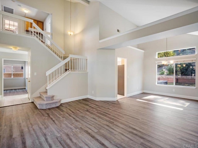 unfurnished living room featuring stairway, baseboards, visible vents, and wood finished floors