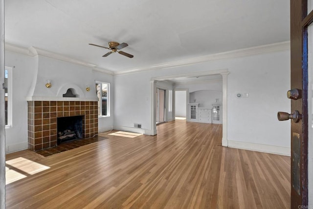 unfurnished living room featuring crown molding, baseboards, wood finished floors, and a tile fireplace