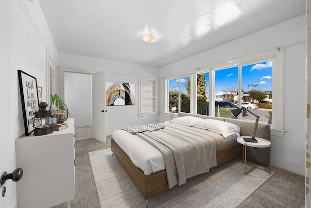 bedroom featuring light carpet and baseboards