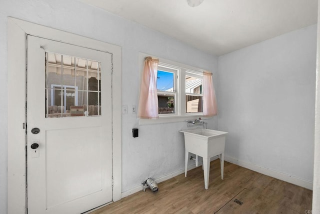 clothes washing area with wood finished floors and baseboards