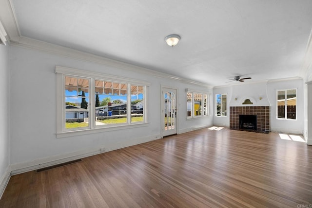 unfurnished living room with crown molding, visible vents, a fireplace, and wood finished floors