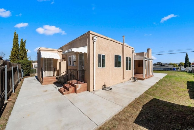 view of property exterior with a patio area, a yard, fence, and stucco siding