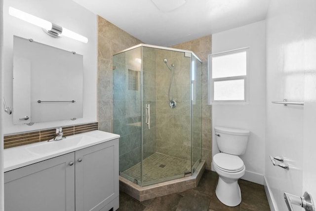 bathroom with tasteful backsplash, toilet, a shower stall, vanity, and baseboards