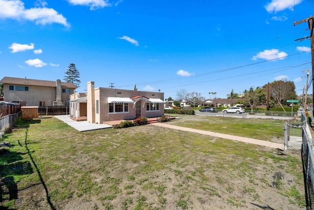 rear view of house featuring a fenced backyard, a lawn, and stucco siding