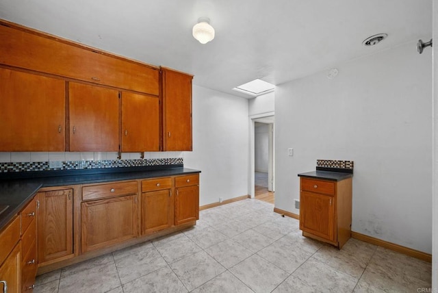 kitchen featuring dark countertops, baseboards, visible vents, and brown cabinetry