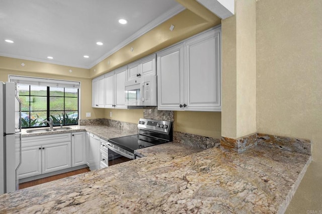 kitchen with a sink, white appliances, ornamental molding, and white cabinetry