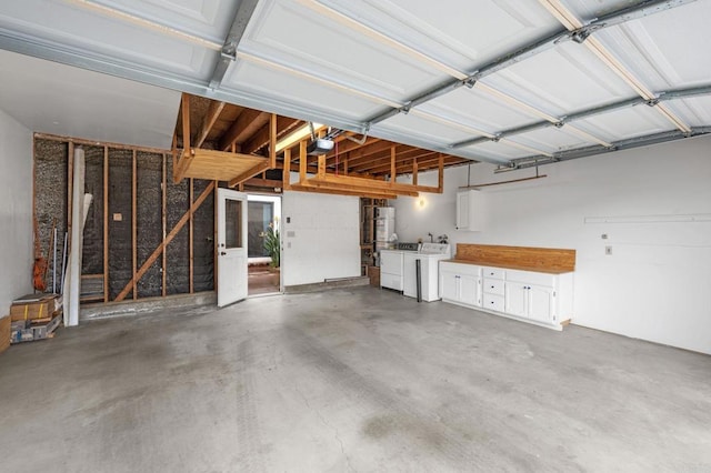 garage with strapped water heater, a garage door opener, and washing machine and clothes dryer