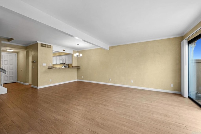 unfurnished living room featuring light wood finished floors, crown molding, baseboards, a chandelier, and beamed ceiling