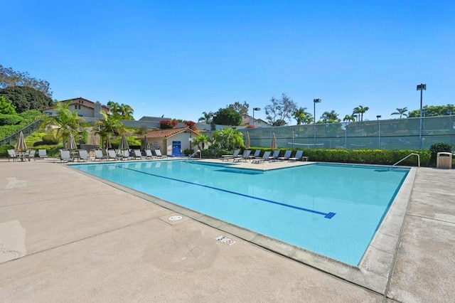 community pool with a patio and fence