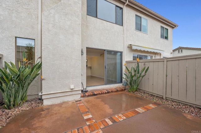 back of house with stucco siding, a patio, and fence