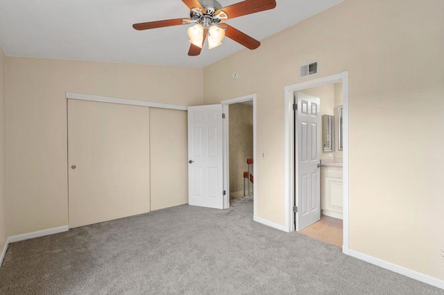 unfurnished bedroom featuring visible vents, ensuite bath, a closet, carpet, and vaulted ceiling