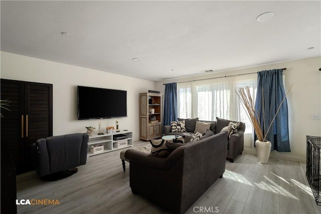 living room featuring baseboards, visible vents, and light wood finished floors