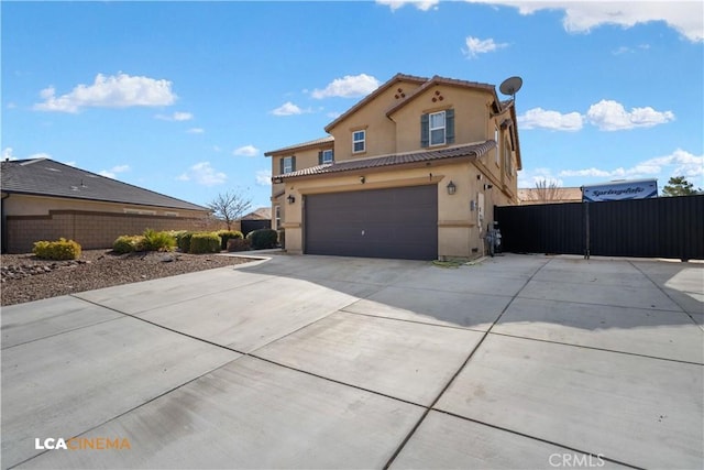 view of front of house with a garage, concrete driveway, a tile roof, fence, and stucco siding