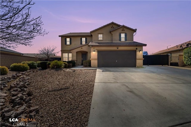 view of front of property with a garage, driveway, a tiled roof, a gate, and stucco siding