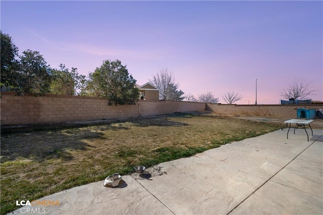 yard at dusk featuring a fenced backyard and a patio