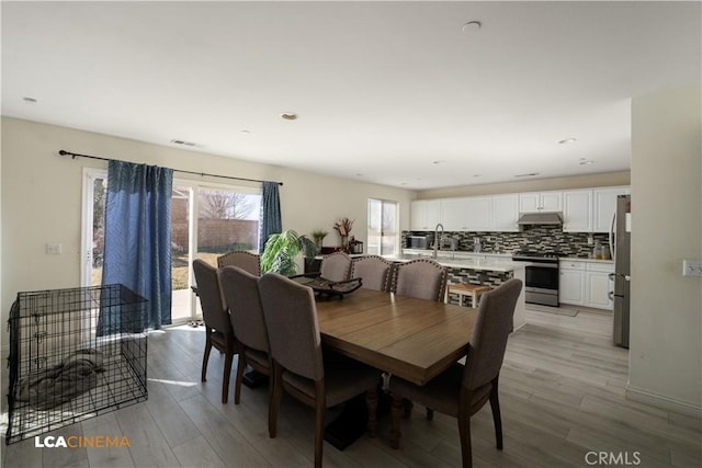 dining area with light wood-style floors and visible vents