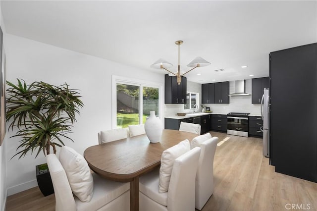 dining area with light wood-style flooring, a notable chandelier, and recessed lighting