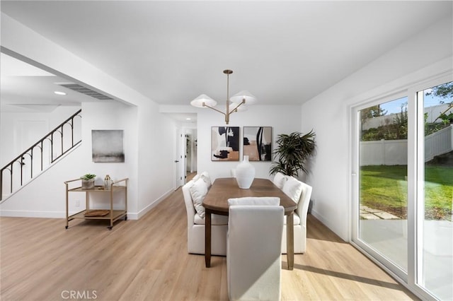 dining area with a notable chandelier, visible vents, baseboards, stairs, and light wood-style floors