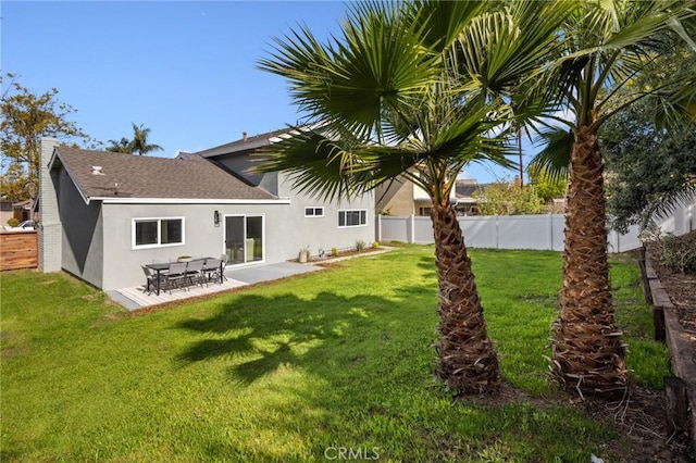 rear view of house featuring a yard, a patio area, a fenced backyard, and stucco siding