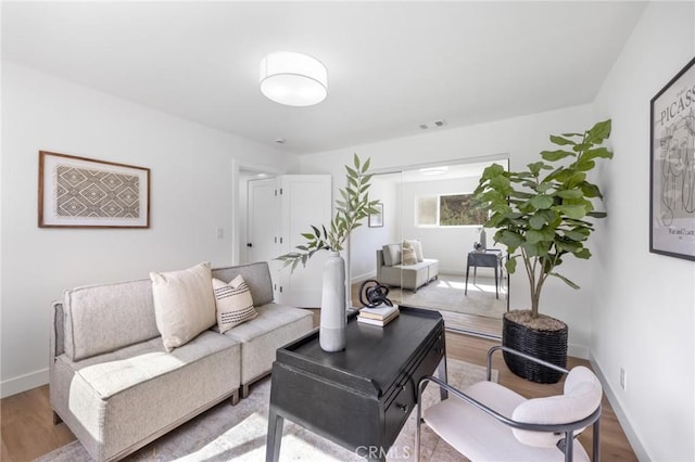 living room with visible vents, baseboards, and wood finished floors