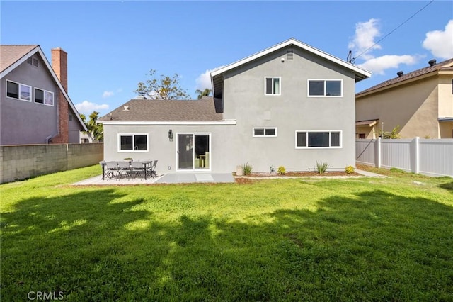 rear view of property featuring a lawn, a fenced backyard, and stucco siding