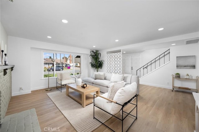 living room with recessed lighting, visible vents, baseboards, stairs, and light wood-style floors