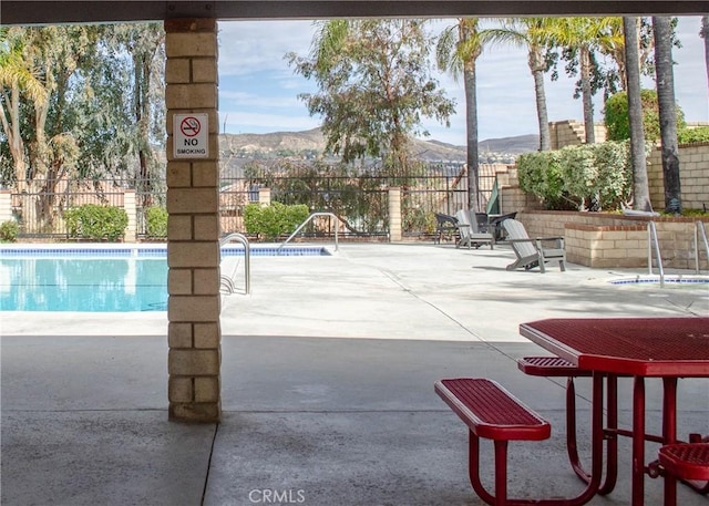 community pool featuring a patio, fence, and a mountain view